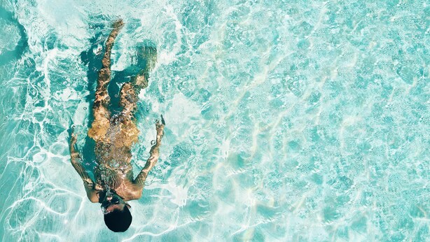 A person swimming in a clear, turquoise pool.