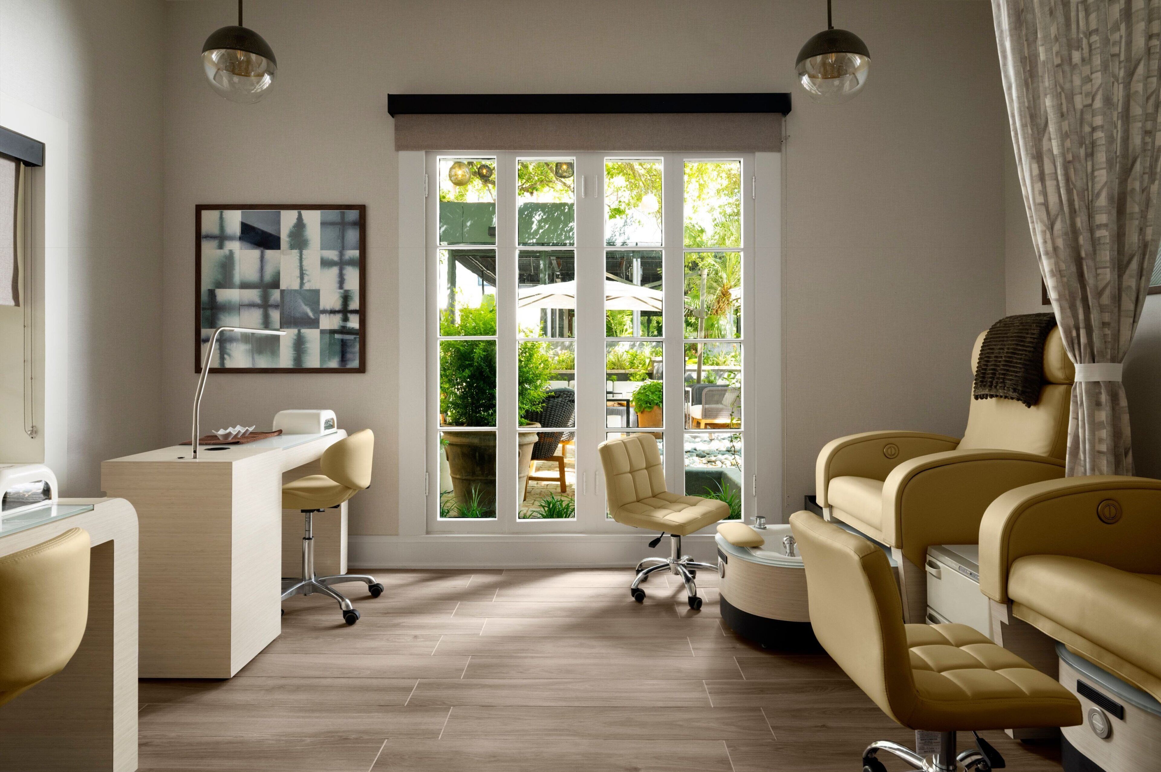 A modern room with a desk, chairs, and a large window with a view of greenery.