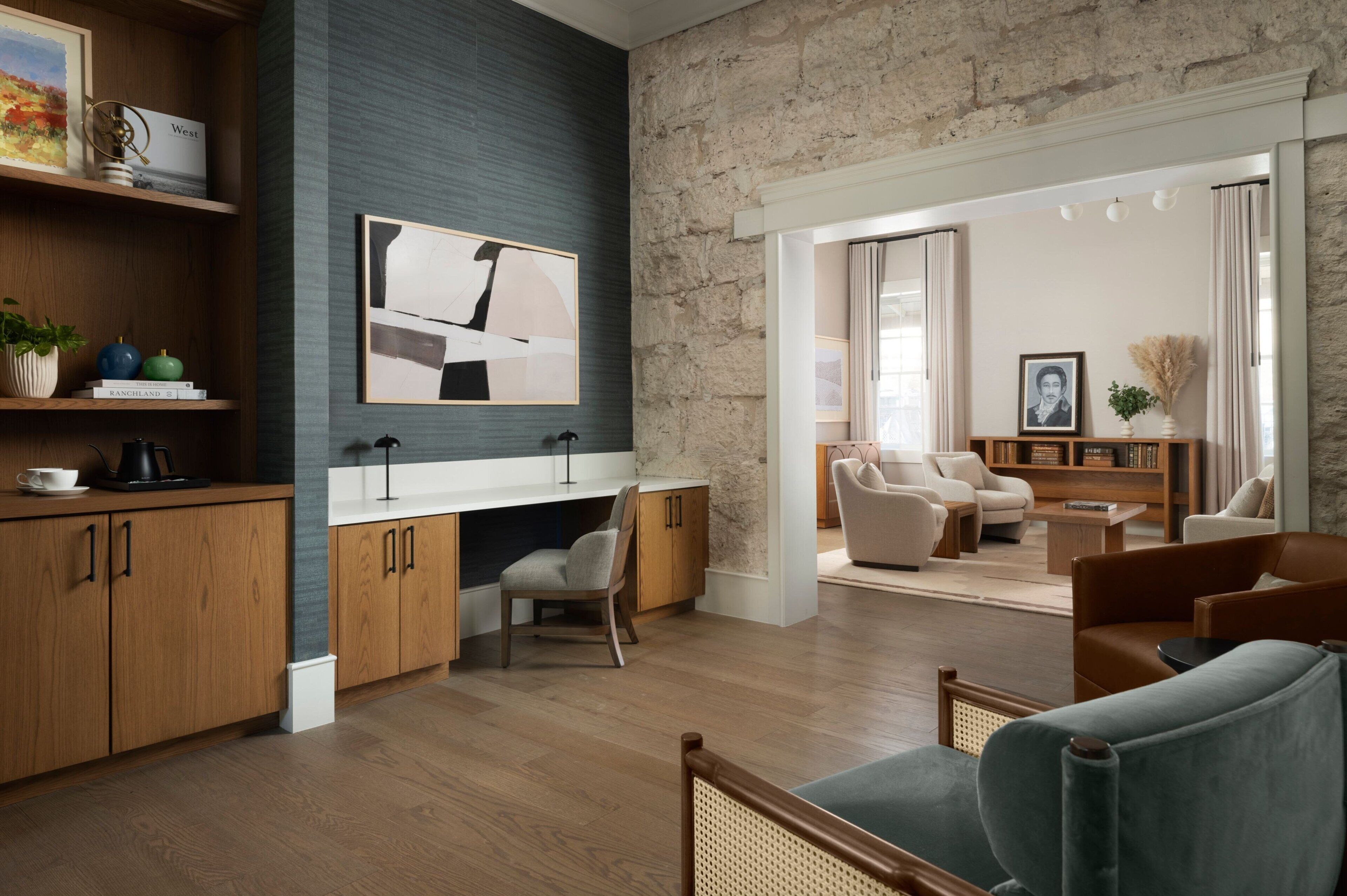 Een moderne woonkamer met een stenen accentmuur, houten meubels en een groot abstract schilderij.