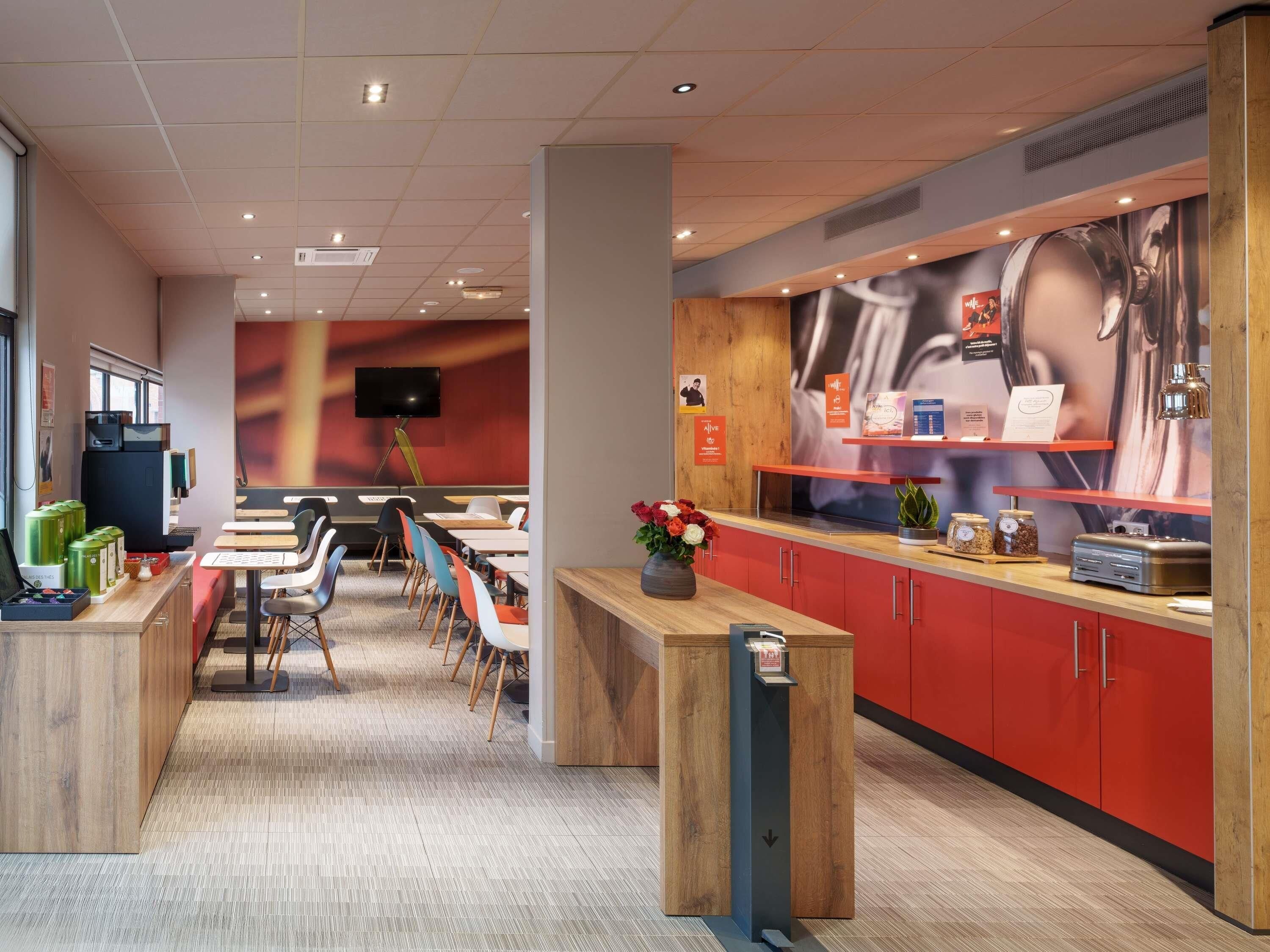 A modern hotel lobby with a reception desk, seating area, and a large screen.
