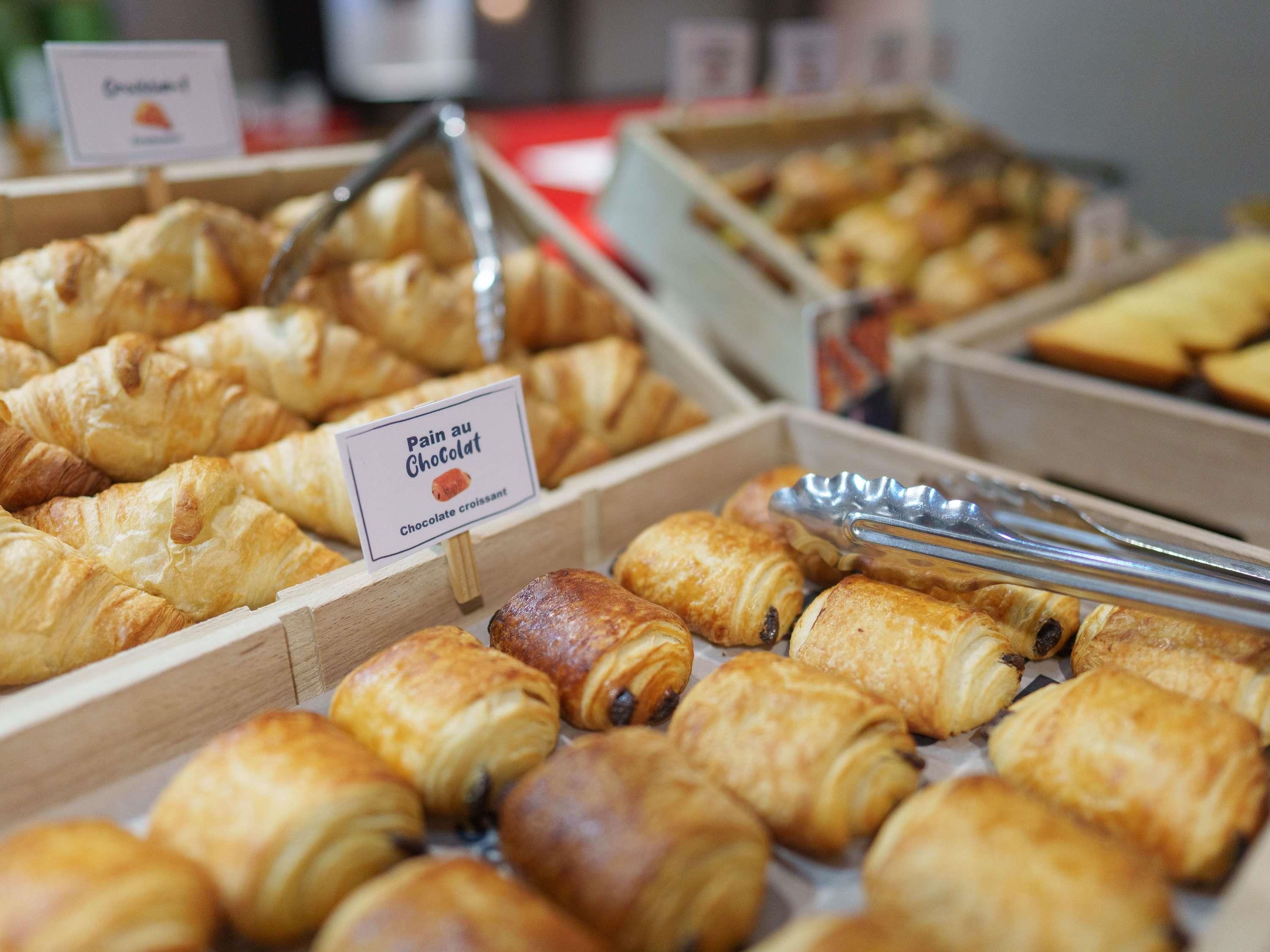 A display of assorted pastries, including chocolate croissants, in a bakery setting.