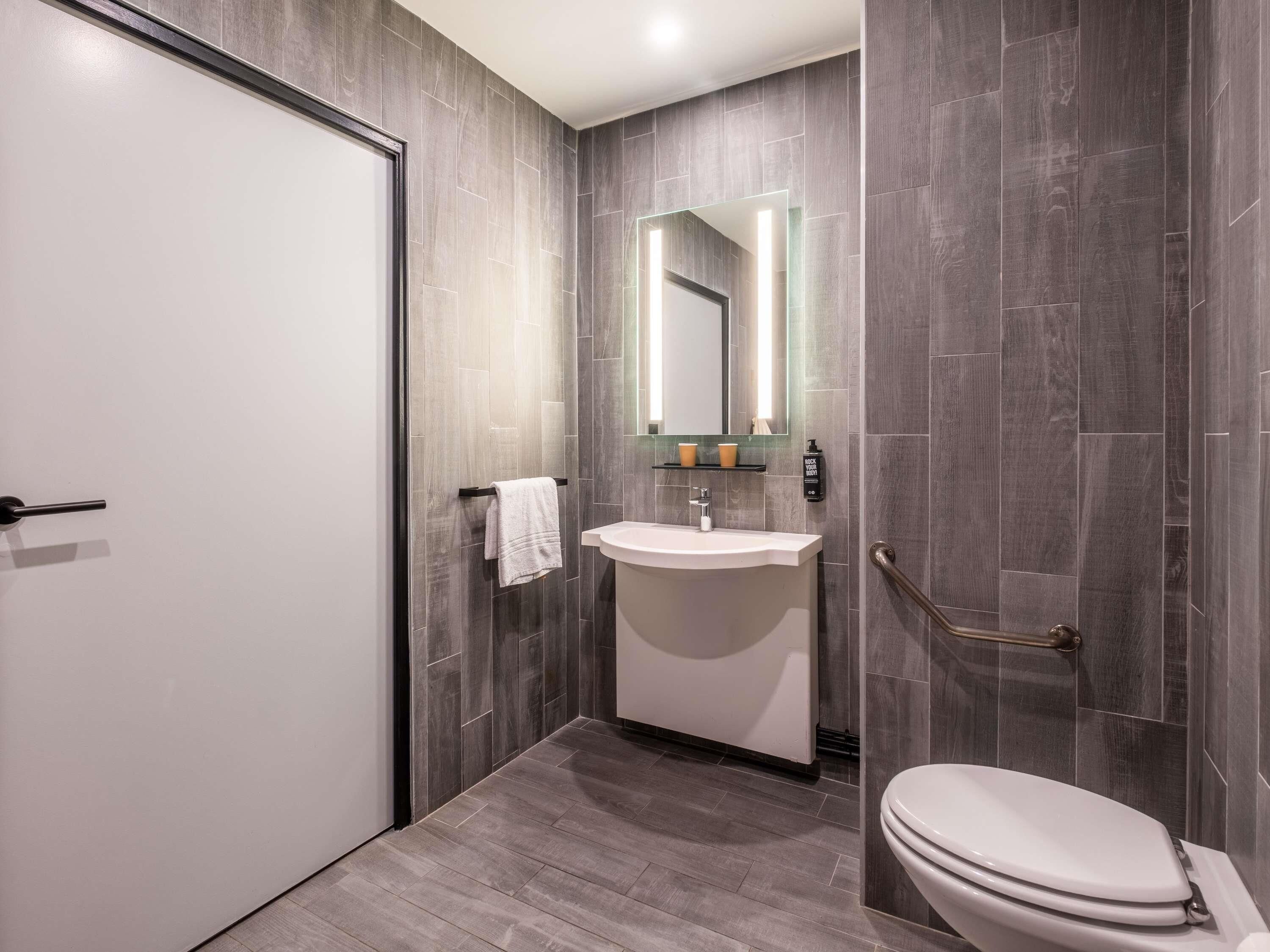 A modern bathroom with a white toilet, a sink, and a mirror.