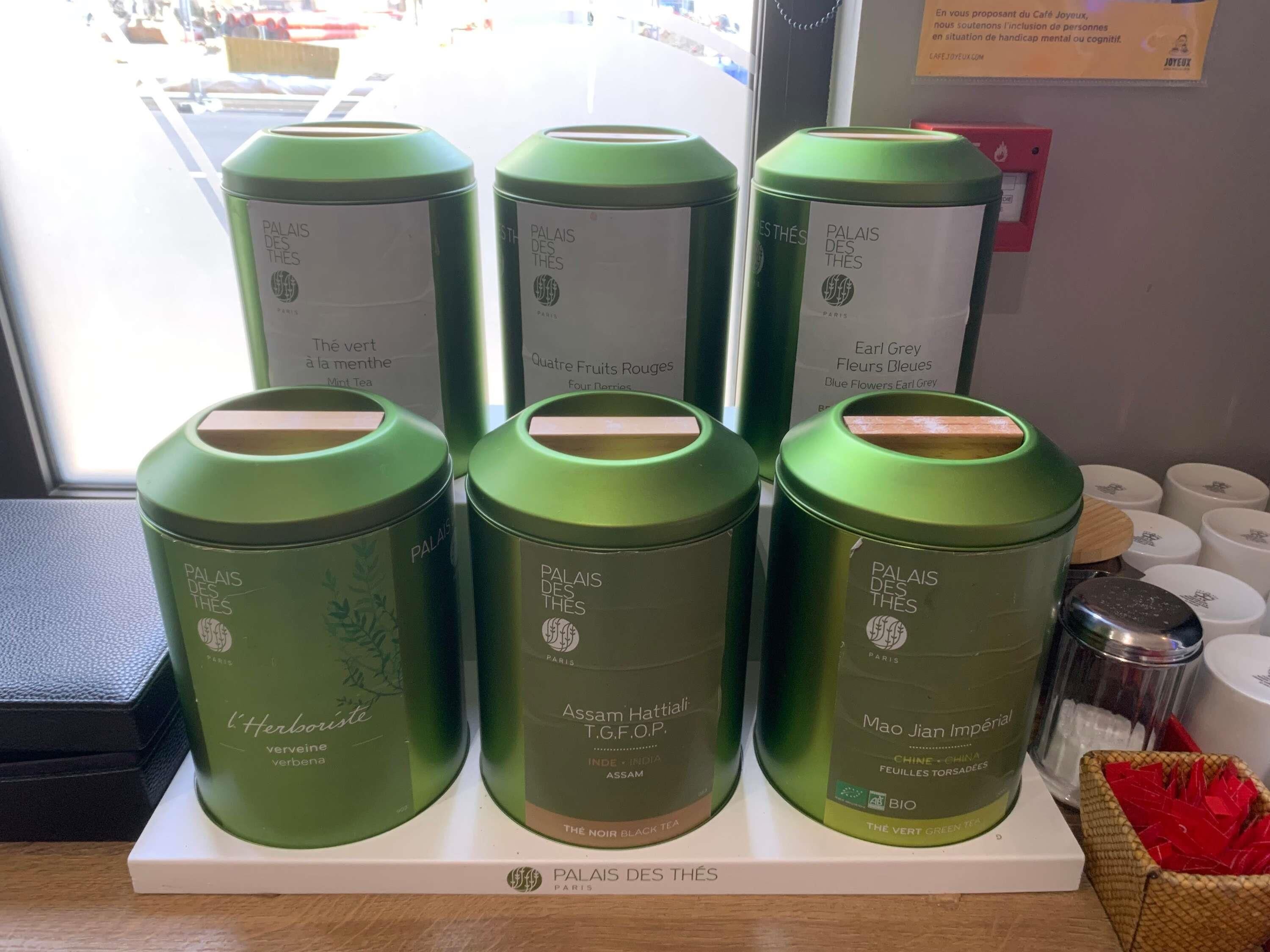 A display of green tea tins with labels indicating different tea varieties and origins.