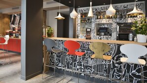 A modern bar area with unique chairs, a patterned wall, and hanging pendant lights.
