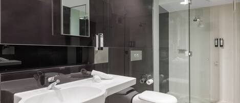 A modern bathroom with a large sink, a toilet, and a glass-enclosed shower.