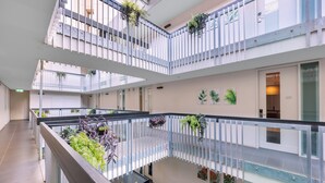 Um átrio com vários níveis, varandas, guarda-corpos de vidro e plantas em vasos.