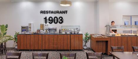 A restaurant with a wooden counter, seating area, and a wall sign indicating the year 1903.