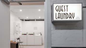 Habitación de hotel con un letrero que dice 'Guest Laundry', un escritorio con una silla y vistas al baño.