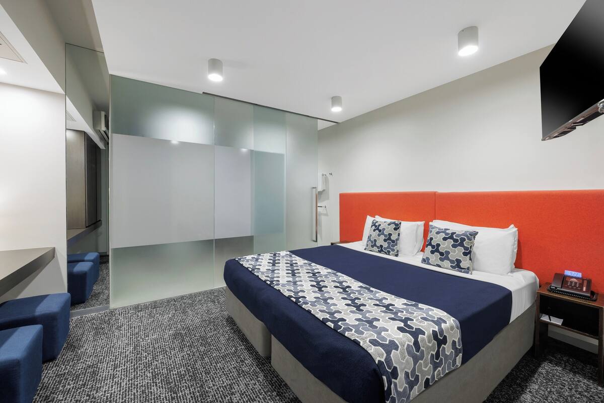 Una habitación de hotel moderna con una cama grande, un escritorio y una zona de estar.