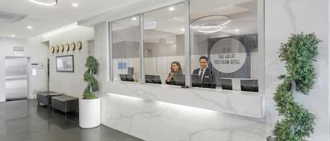 Een receptiebalie met een glazen scheiding, een klok en een bord met de tekst 'THE GREAT SOUTHERN HOTEL'.