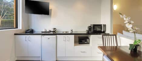 Una cocina moderna con gabinetes blancos, microondas integrado y cafetera.