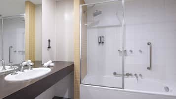 A modern bathroom with a glass-enclosed shower, a sink with two faucets, and a bathtub.