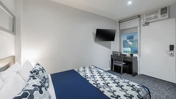 A hotel room with a bed, a desk, a chair, a TV, and a sliding door.