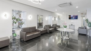 Um lobby moderno com sofás de couro, uma mesa de centro de mármore e plantas em vasos.