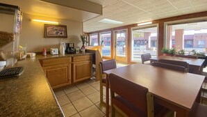 A restaurant with a counter, wooden cabinets, and a dining area with tables and chairs.