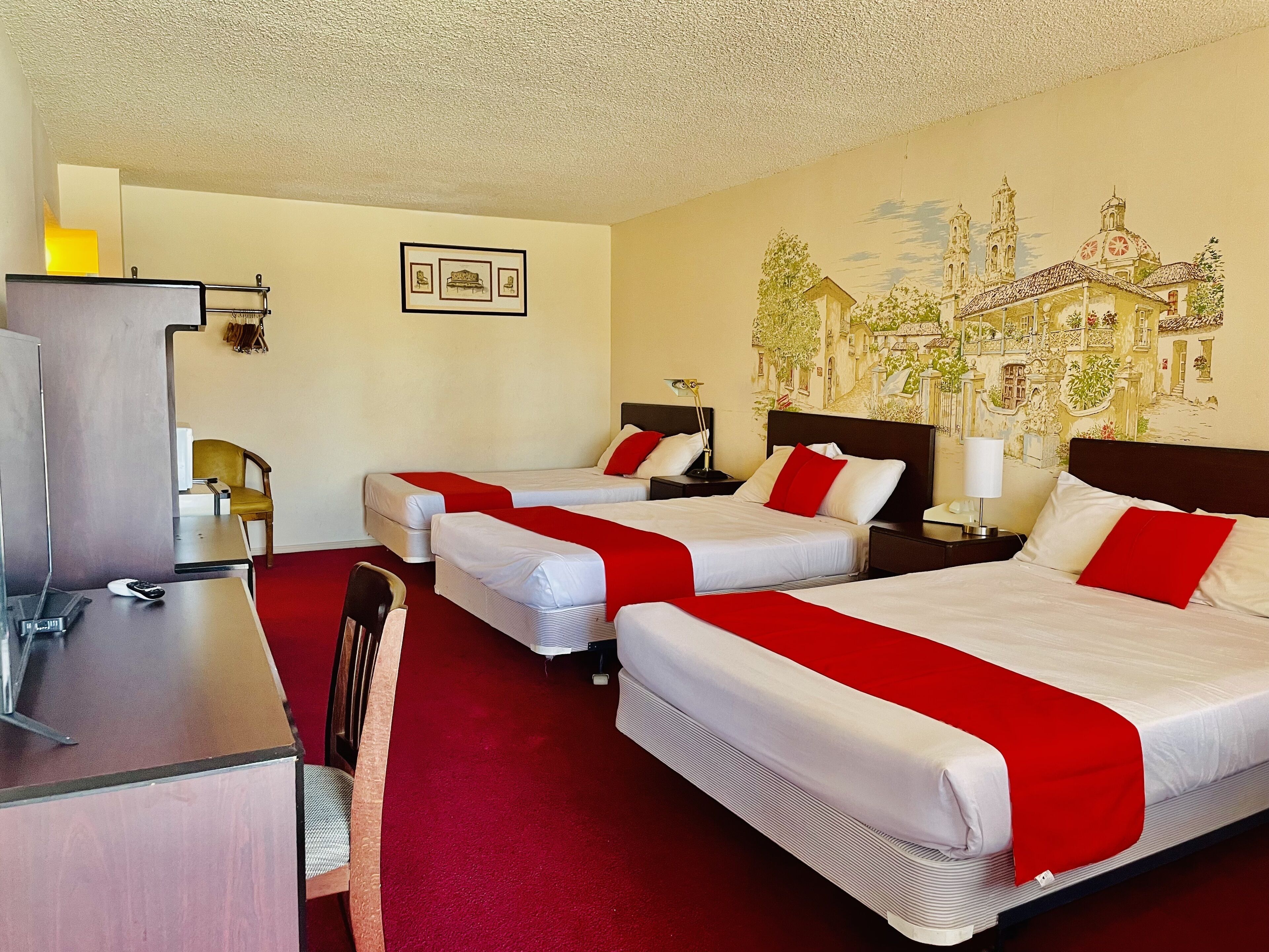 Habitación de hotel con dos camas, un escritorio y una silla.