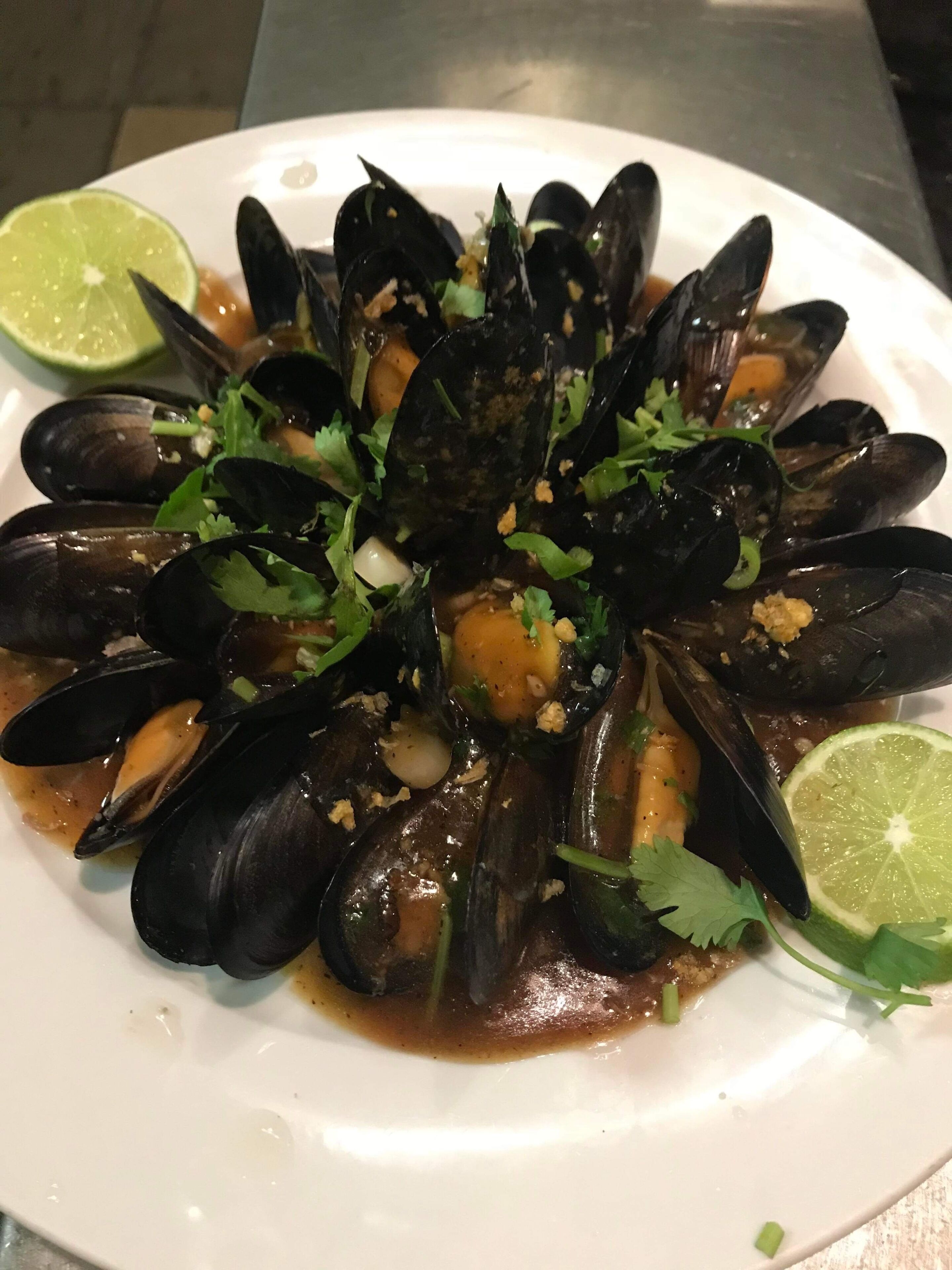 A plate of mussels garnished with herbs and lime.