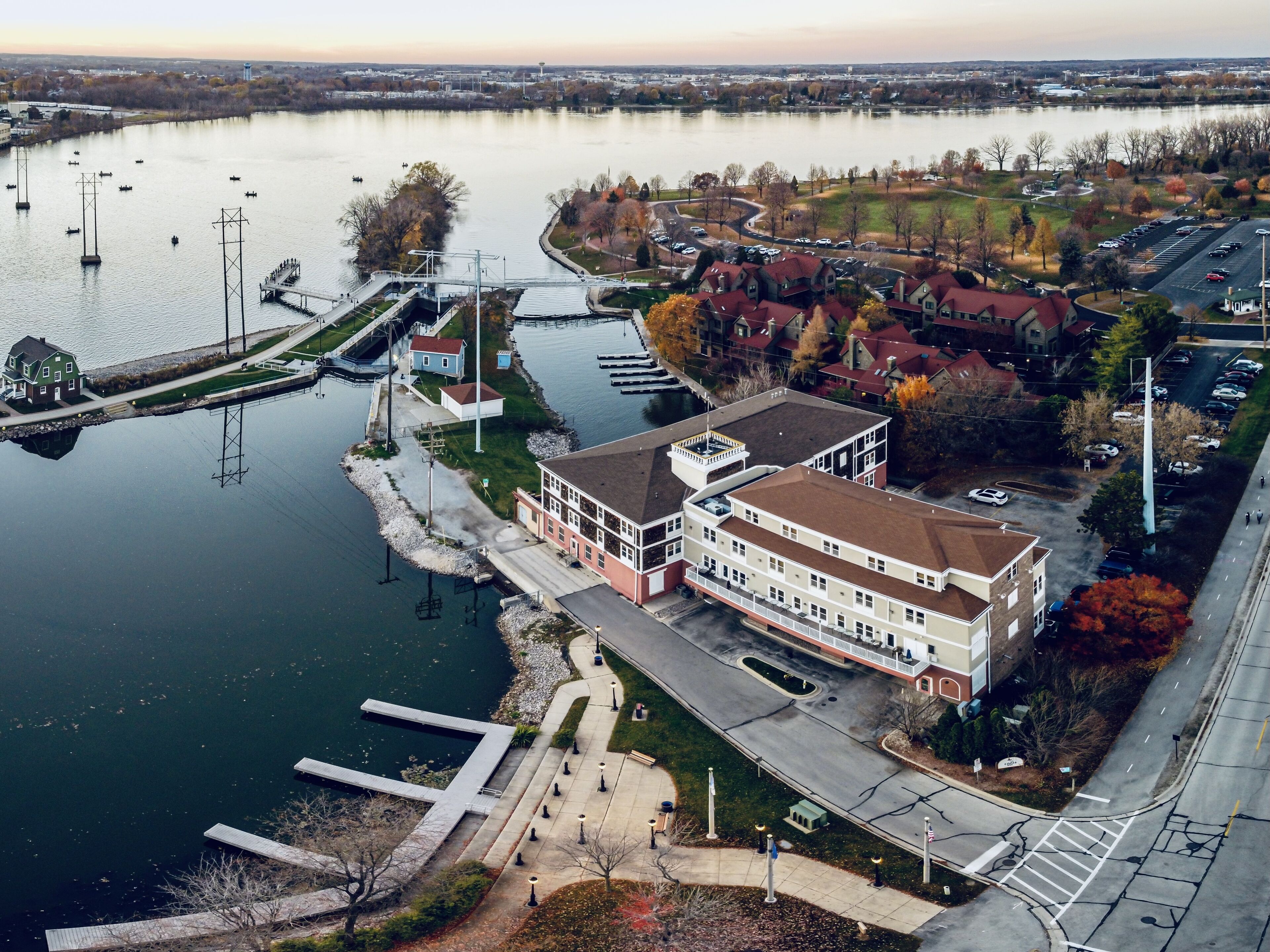 A riverside hotel with a dock, a parking lot, and a pedestrian walkway.