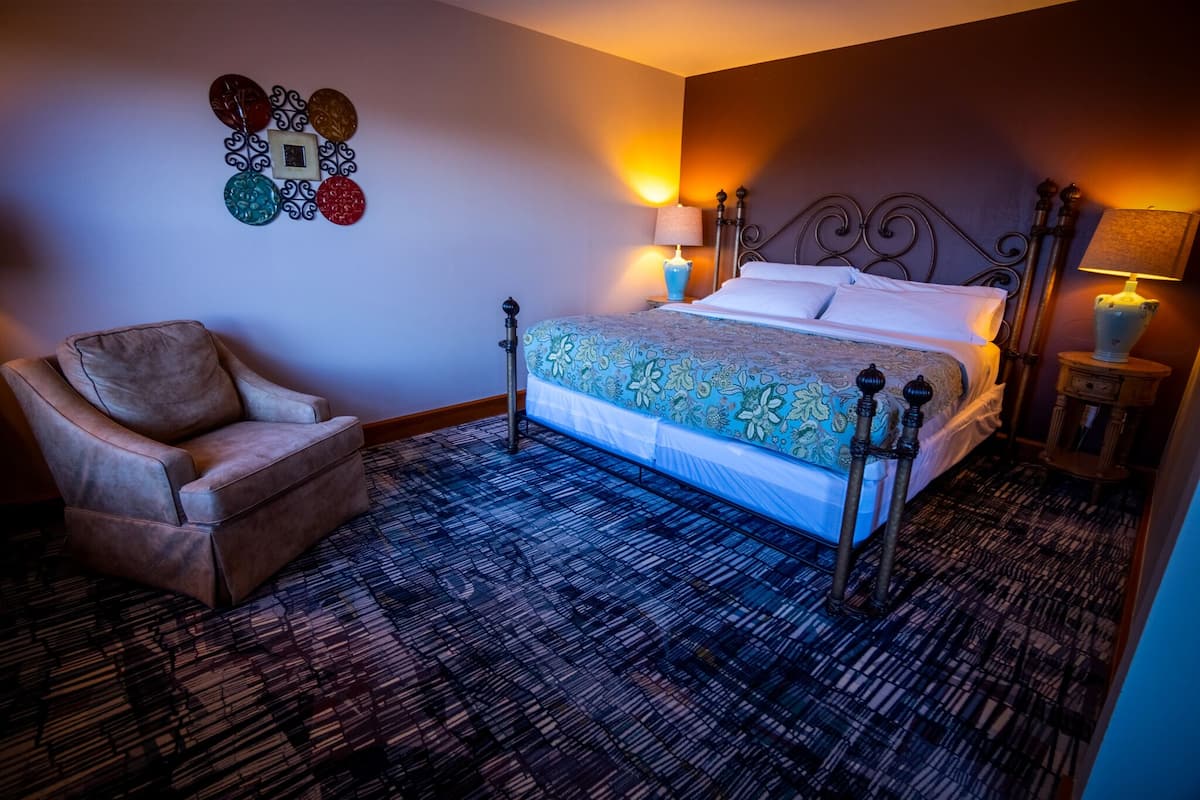 A hotel room with a bed, a chair, and decorative wall art.