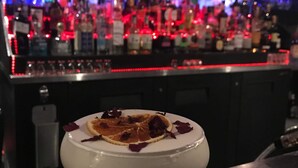Un bar proposant un large choix de bouteilles, avec un verre à martini décoré d’un accompagnement sucré, le tout posé sur un comptoir en marbre.