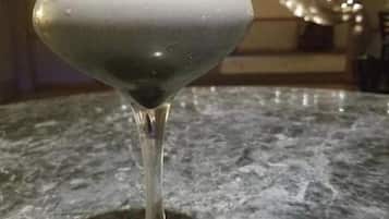 Una copa de martini con un líquido transparente sobre una encimera de mármol.