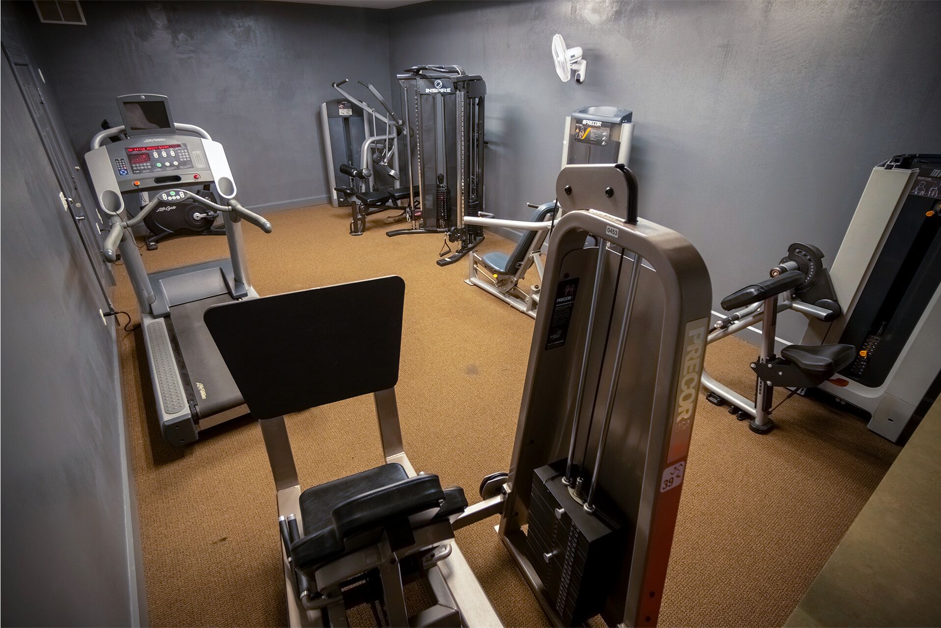 Une salle de sport équipée de divers appareils d’exercice, notamment des tapis de course, des appareils de musculation et un banc de développé couché.