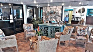 Un vestíbulo con muebles de mimbre, una mesa central con adornos y un mostrador azul.