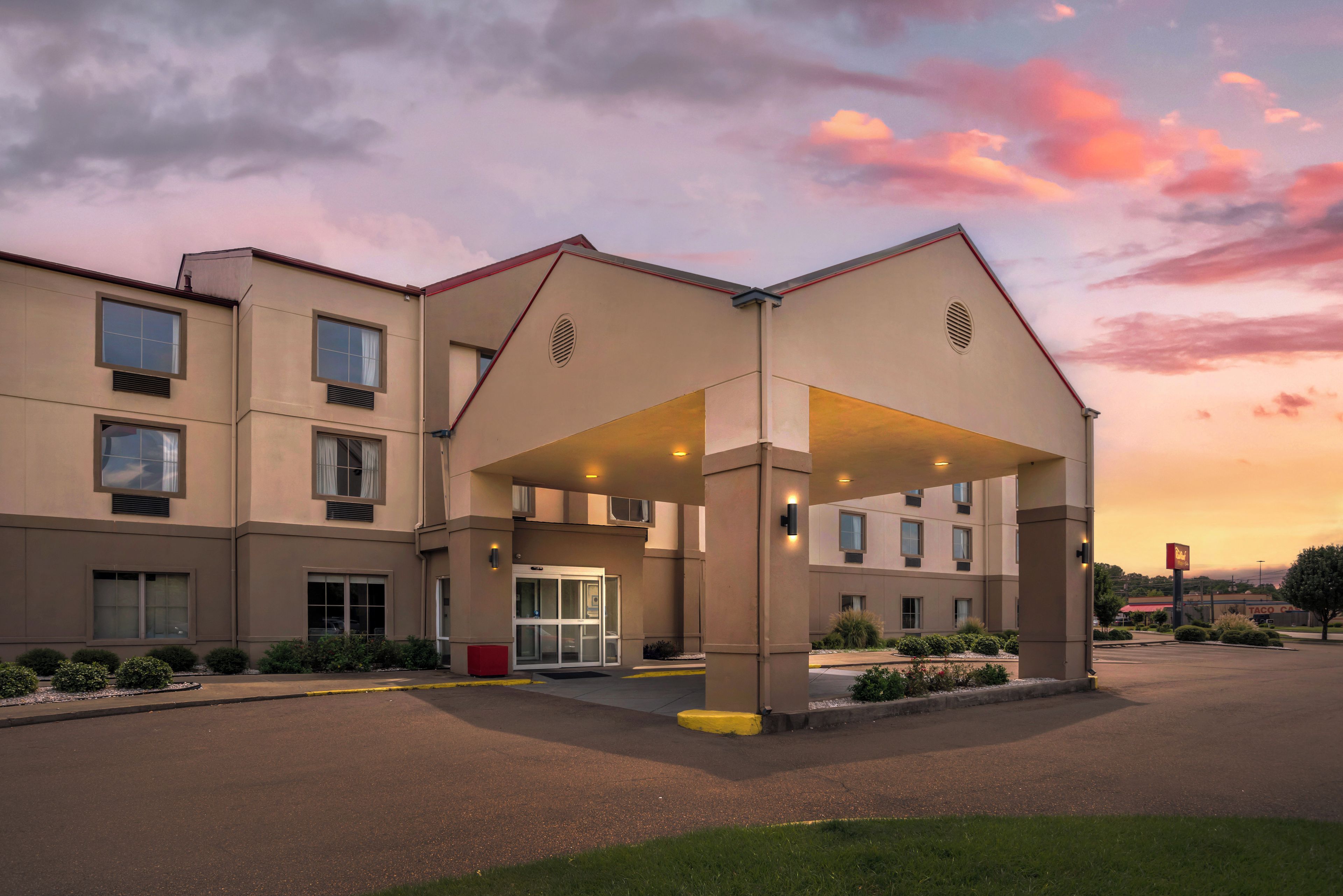 A multi-story hotel with a covered entrance and a parking lot.