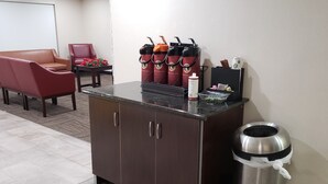 Un espace d’accueil d’hôtel comprenant un meuble brun, une poubelle et un coin café avec plusieurs distributeurs.