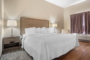 Une chambre d’hôtel avec un grand lit, des lampes de chevet, une chaise et une fenêtre avec des rideaux.