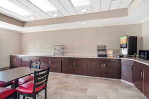 A modern kitchen area with a dining table and chairs, a coffee machine, and a microwave.