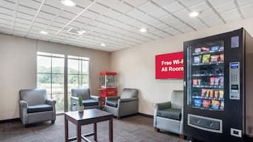 A hotel room with a seating area, a vending machine, and a sign indicating free Wi-Fi availability.