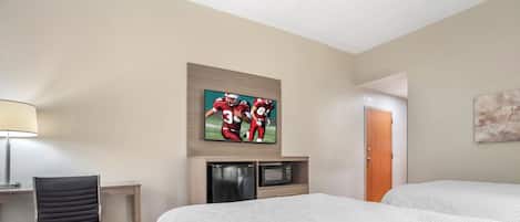 Una habitación de hotel con una cama, un escritorio con lámpara, un microondas y una obra de arte en la pared.