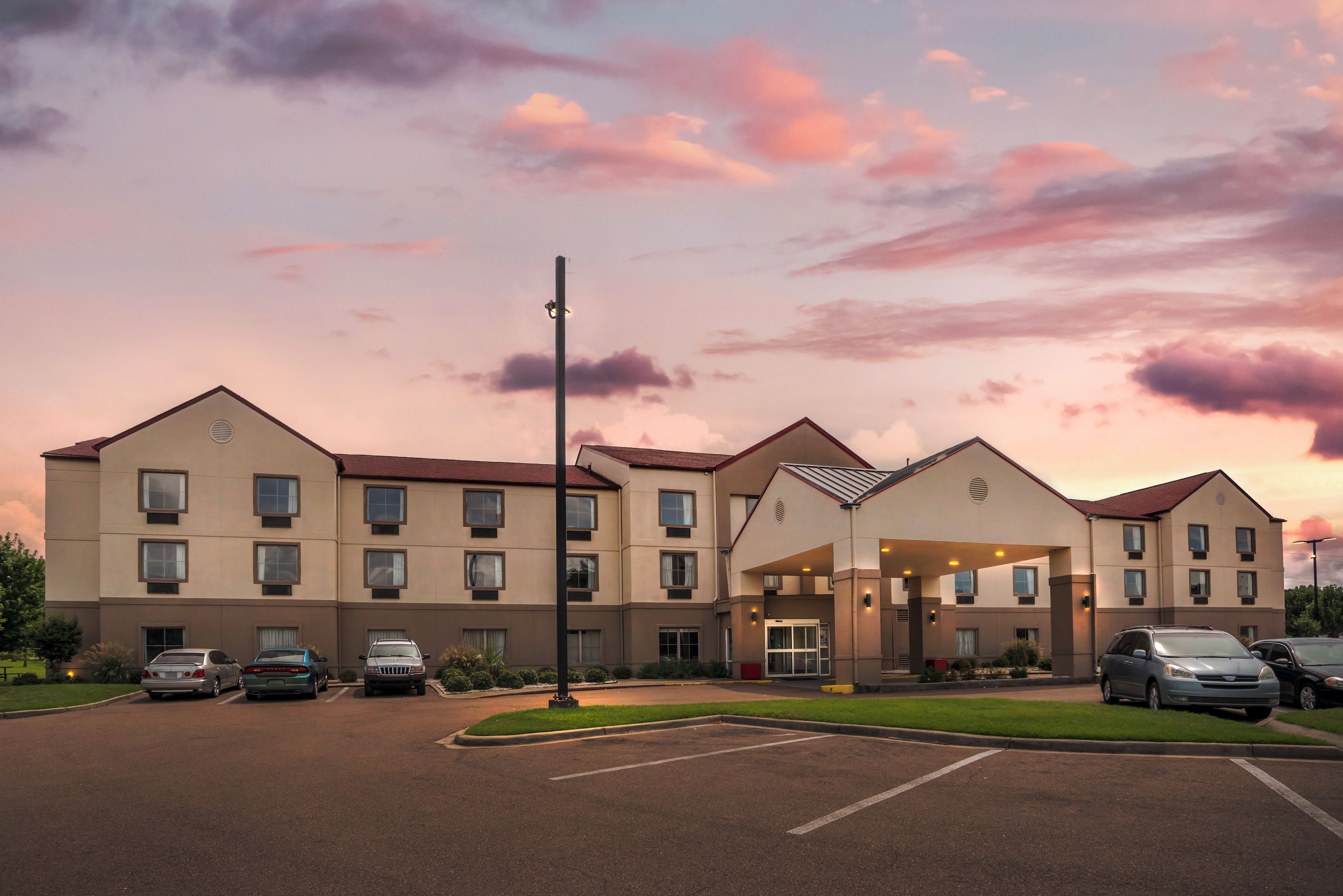 A multi-story hotel with a central entrance and parking lot.