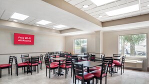 Un grand espace dédié à la salle à manger, avec plusieurs tables et chaises, un panneau indiquant que le Wi-Fi est gratuit, et de grandes fenêtres qui laissent entrer la lumière naturelle.