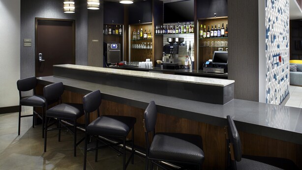 A bar area with a counter, bar stools, and shelves of bottles. - Hyatt Place Atlanta Downtown (Atlanta)