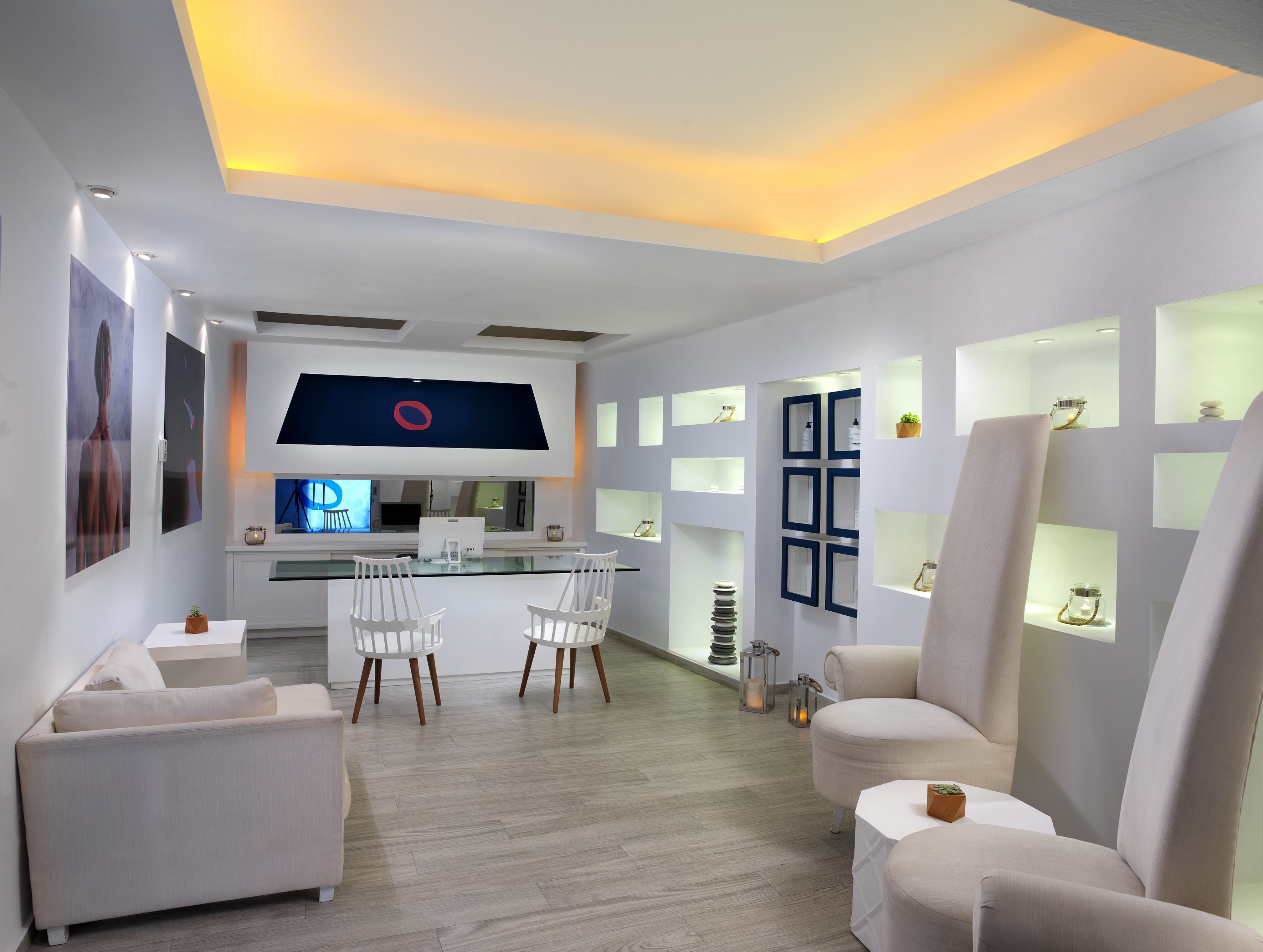 A modern, well-lit room with a large flat-screen TV, white furniture, and built-in shelves with decorative items.