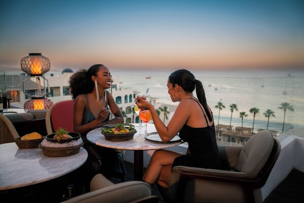 Dos personas cenando en una mesa con vista al océano.