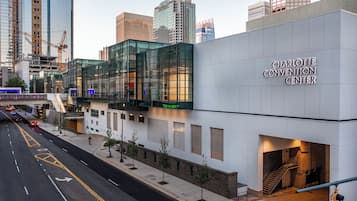 El Centro de Convenciones Charlotte, con fachada de vidrio moderna, entrada para muelles de carga y una escalera que lleva a un nivel superior.