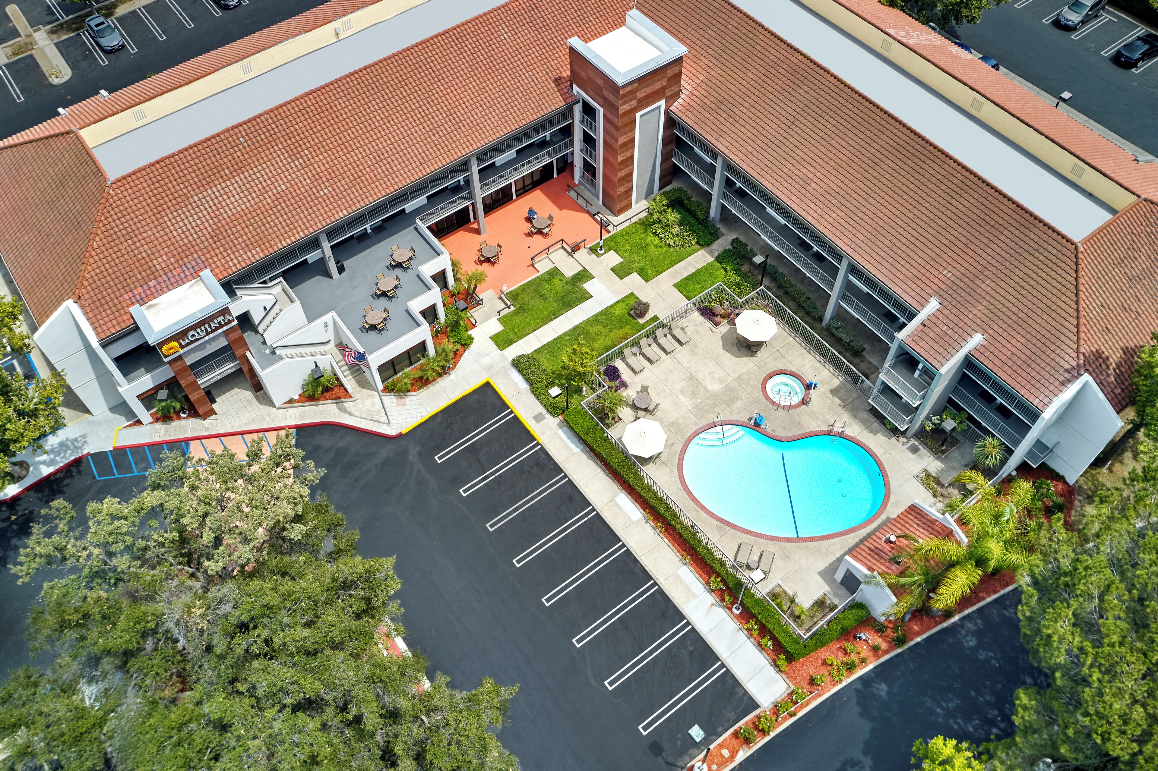 Vista aérea de un hotel con piscina, mobiliario exterior y aparcamiento.