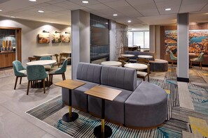 A modern hotel lobby with seating areas, artwork on the walls, and a large window with a view. - La Quinta Inn & Suites by Wyndham Thousand Oaks-Newbury Park (Thousand Oaks)
