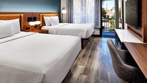 A hotel room with two beds, a desk, a chair, a TV, and a view of the outside. - La Quinta Inn & Suites by Wyndham Thousand Oaks-Newbury Park (Thousand Oaks)