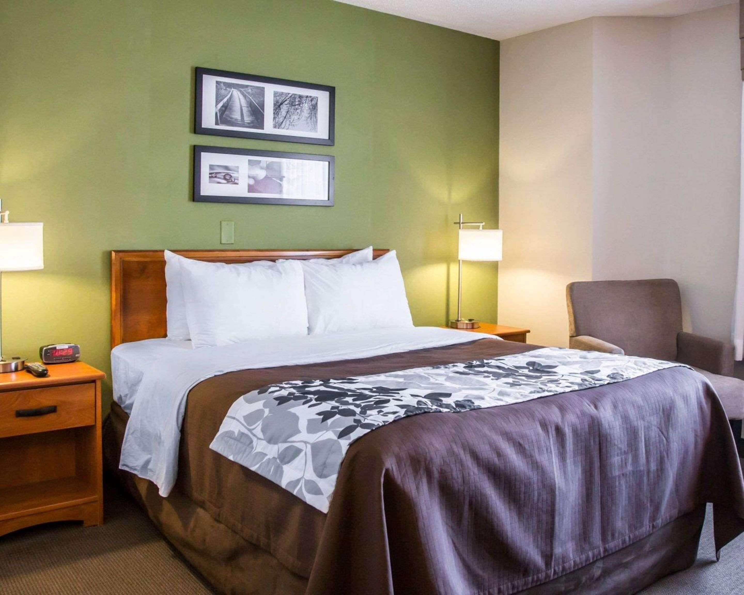 A hotel room with a bed, two bedside tables, a chair, and two wall-mounted lamps.