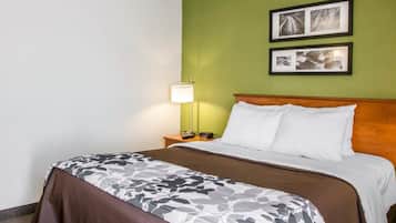 A hotel room with a bed, a nightstand, a lamp, and two framed pictures on the wall.