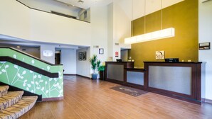 A hotel reception area with a staircase, reception desk, and a large potted plant. - Sleep Inn Midway Airport Bedford Park (Chicago)