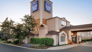 A Sleep Inn hotel with a prominent tower, a covered entrance, and a landscaped front yard. - Sleep Inn Midway Airport Bedford Park (Chicago)