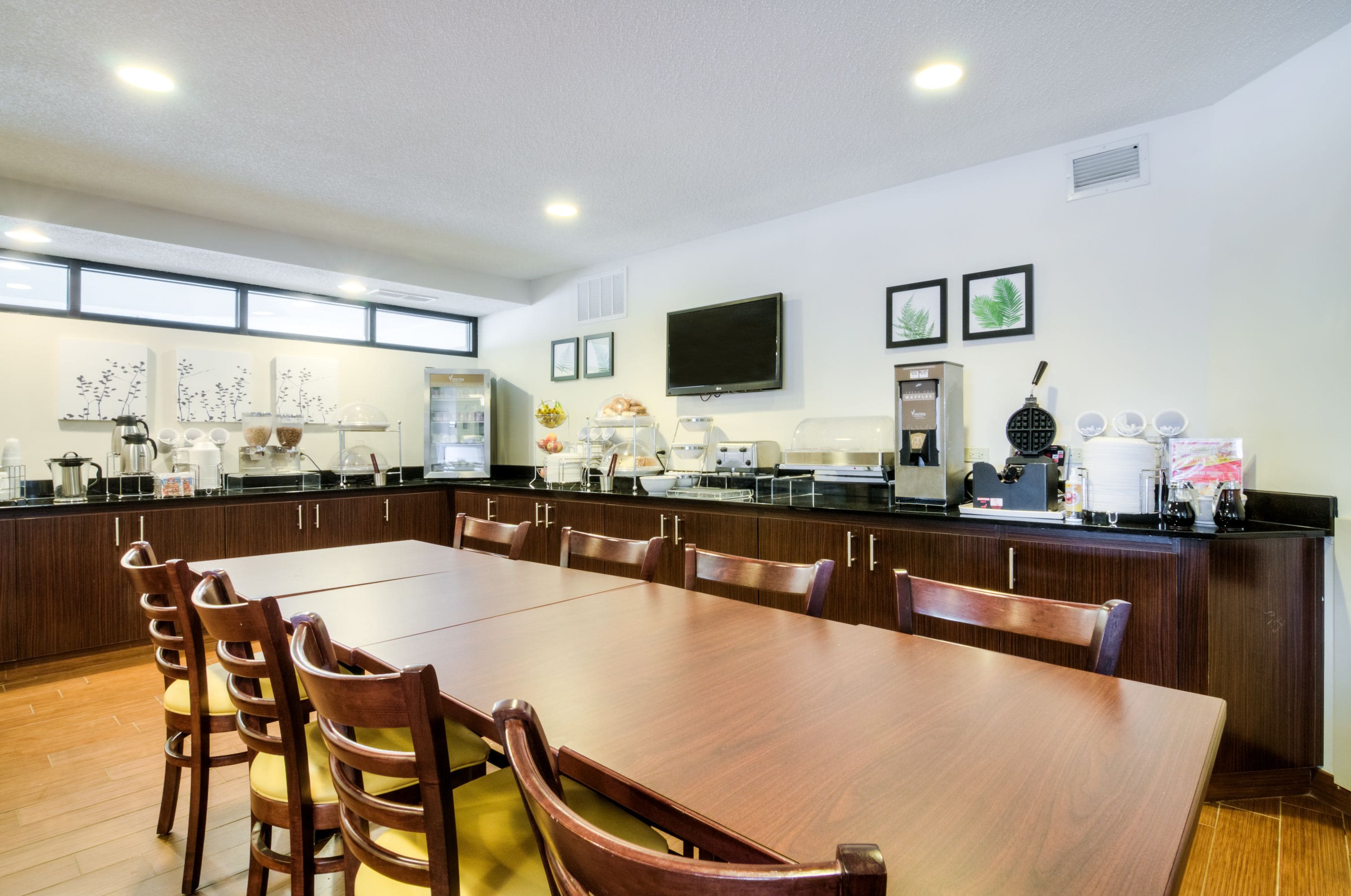 A spacious dining area with a long wooden table and chairs, equipped with a coffee machine and a microwave.