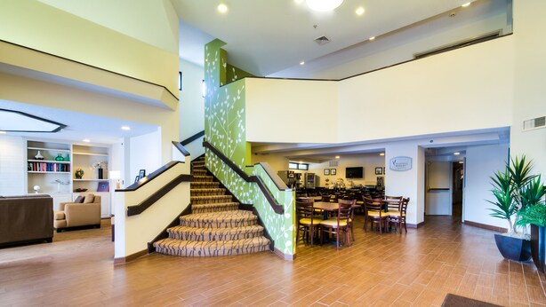 A spacious lobby with a wooden floor, a staircase with a green accent, and a reception area with a sign reading "Welcome". - Sleep Inn Midway Airport Bedford Park (Chicago)