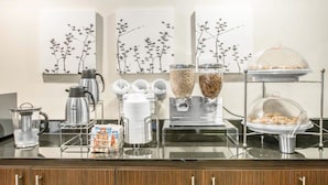 A buffet setup with coffee machines, milk dispensers, and food containers. - Sleep Inn Midway Airport Bedford Park (Chicago)