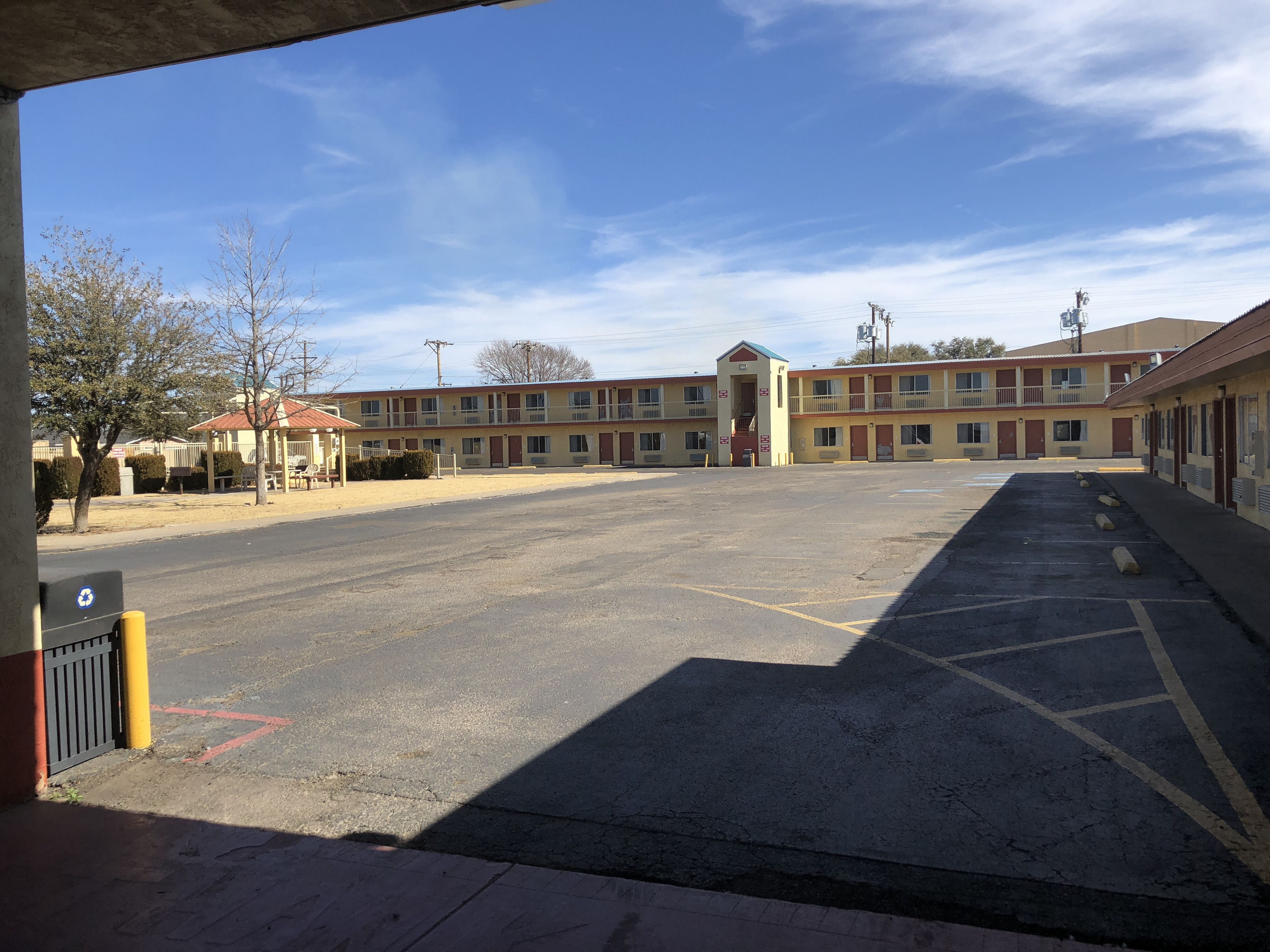 A motel with a large parking lot, a central entrance, and multiple motel rooms.
